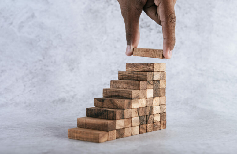 Stacking wooden blocks is at risk in creating business growth ideas.